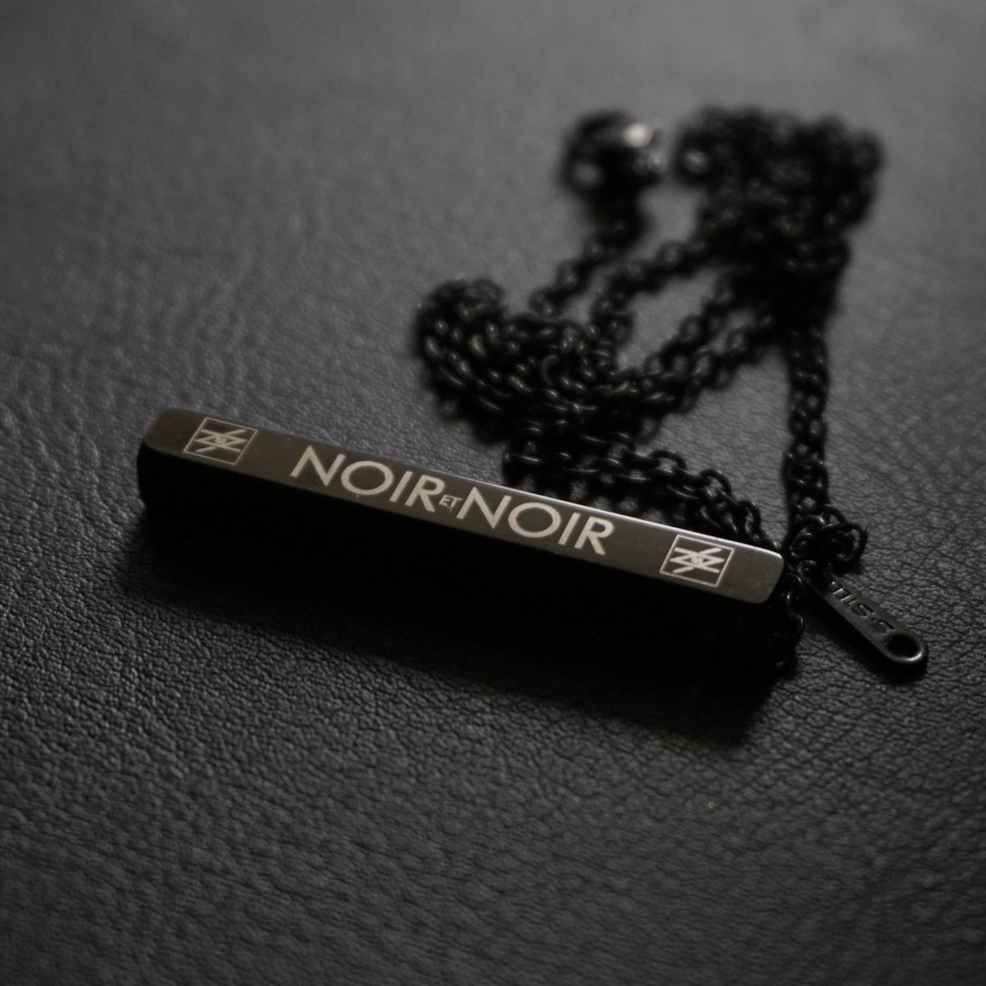 Noir et Noir Rectangular Minimalist Stainless Steel Bar Pendant necklace with black chain on textured background