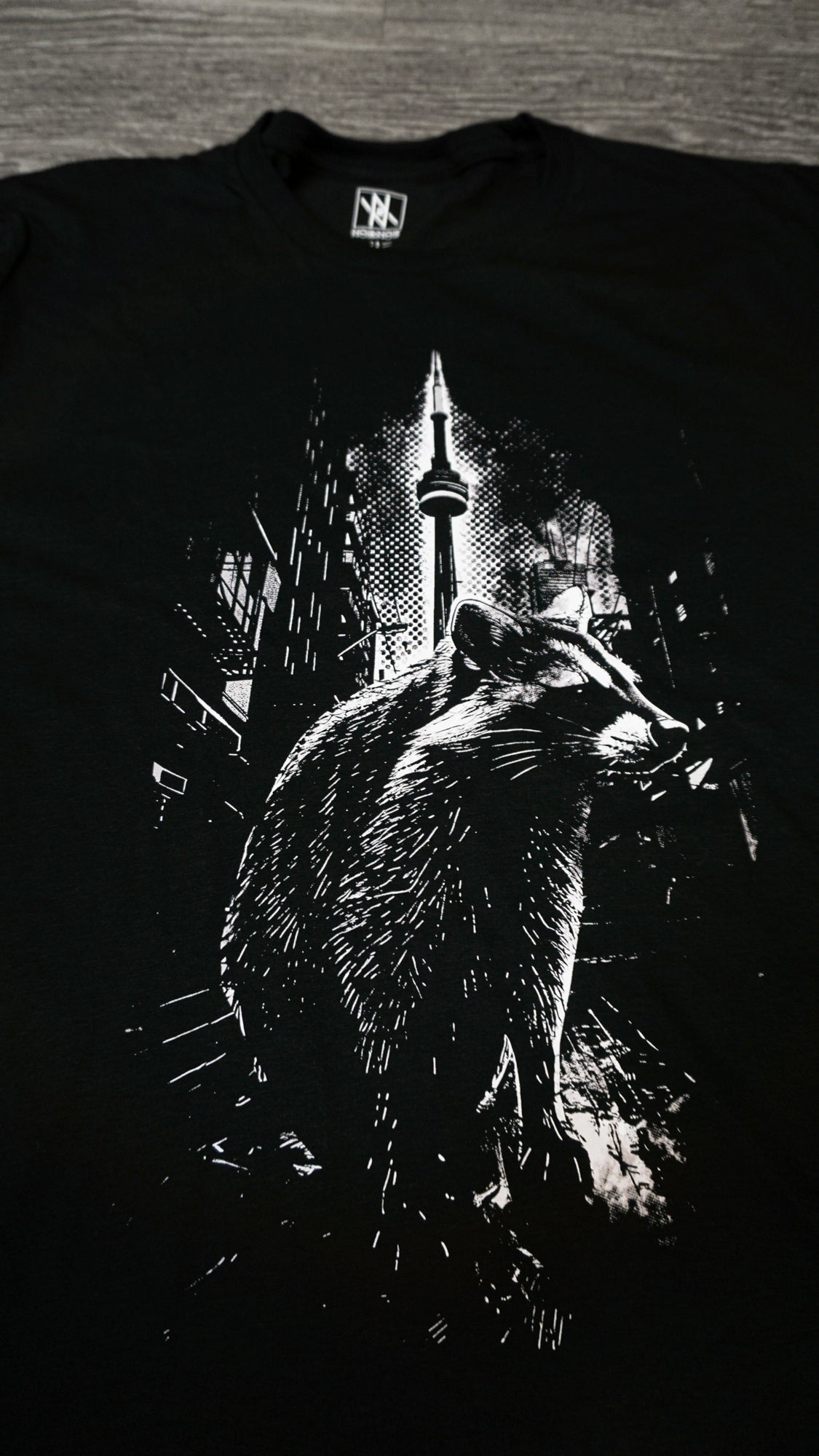 Close-up of the Noir et Noir Toronto Urban Raccoon T-shirt design, highlighting the detailed and intricate black-on-black raccoon print. Ideal for those who appreciate subtle yet artistic style. Part of the exclusive Toronto Collection