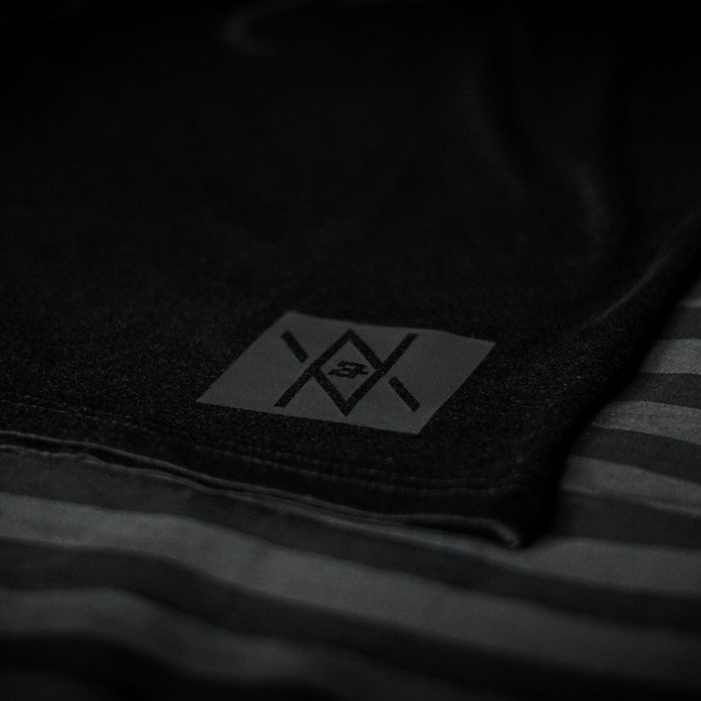 Detailed view of the Noir et Noir GOAT unisex T-shirt's black-on-black logo, highlighting the precision and quality of the matte print. Essential for a modern, minimalist wardrobe. Featured in the Design Collection.