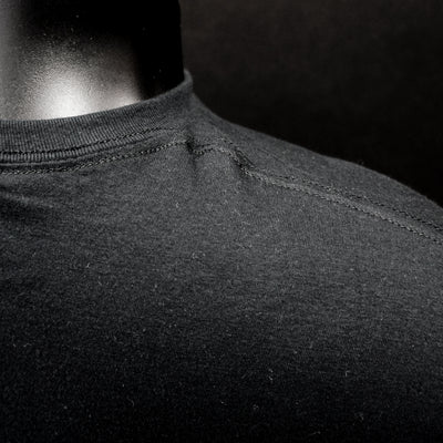 Close-up of black fabric stitching T-Shirt, with a rib collar and smooth texture.