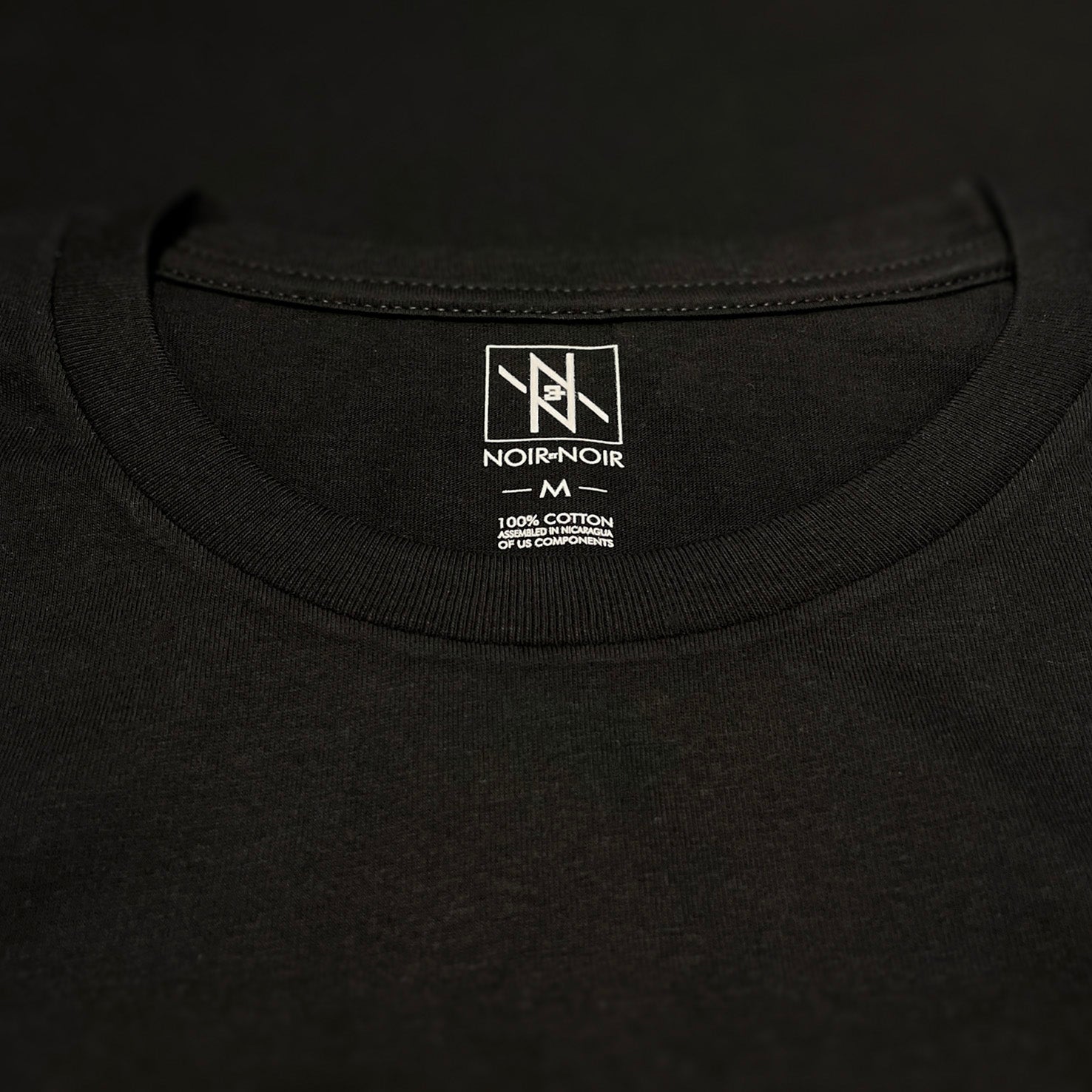 Close-up of the Noir et Noir branding label and collar detail on the Moose unisex T-shirt, showcasing premium craftsmanship and attention to detail. Part of the elegant Design Collection.