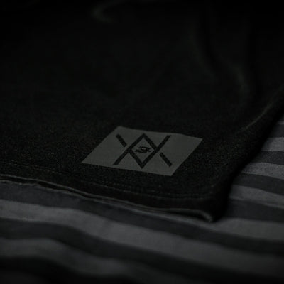 Detailed view of the Noir et Noir Raven unisex T-shirt's black-on-black logo, highlighting the precision and quality of the print. Essential for a modern, minimalist wardrobe. Featured in the Design Collection.